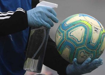 A ball boy disinfects a ball during a Uruguayan tournament football match between Nacional and Penarol at the Centenario stadium in Montevideo on August 9, 2020, amid the COVID-19 novel coronavirus pandemic. - The match is played behind closed doors as a preventive measure against the spread of COVID-19. (Photo by Pablo PORCIUNCULA / AFP)
