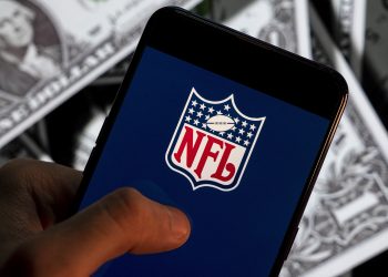 CHINA - 2021/04/23: In this photo illustration the American football league, The National Football League (NFL) logo seen displayed on a smartphone with USD (United States dollar) currency in the background. (Photo Illustration by Budrul Chukrut/SOPA Images/LightRocket via Getty Images)