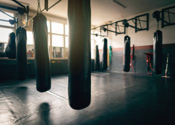 Black heavy bags in an empty gym with a lot of sunlight.