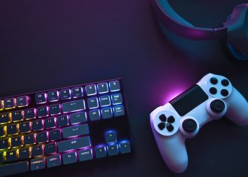 Top down view of colorful illuminated gaming accessories laying on table. Professional computer game playing, esport business and online world concept.